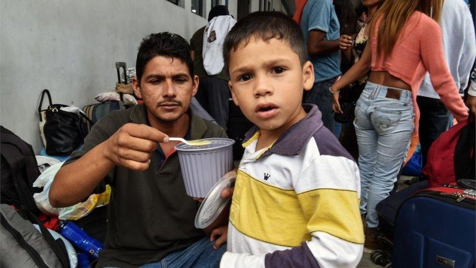 A Venezuelan migrant feeds his child, as they wait at the binational border attention centre (CEBAF) in Tumbes, northern Peru