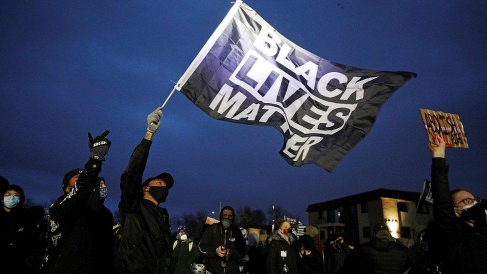 Protesters wave a Black Lives Matter flag outside the Brooklyn Center Police Department. 14 April 2021