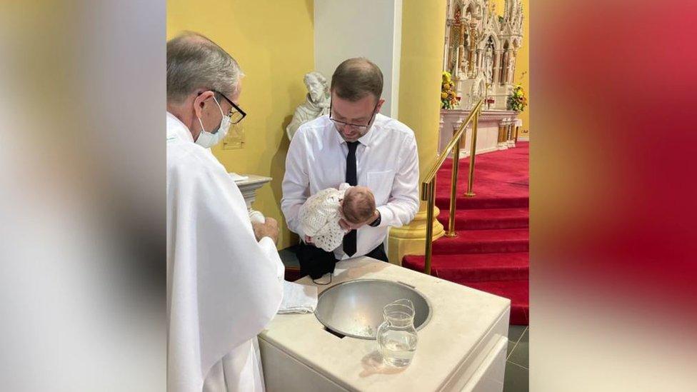 Josh Willis holding his daughter Eviegrace above the bathing pool in the church at her christening on Sunday