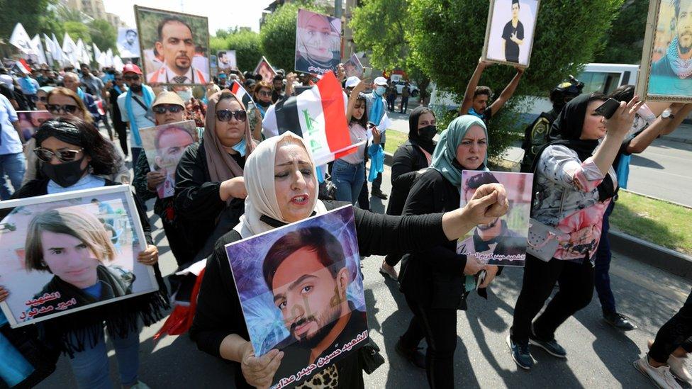 Iraqis carry the images of protesters who were killed in the 2019-2020 unrest at a demonstration in Baghdad on 1 October 2021