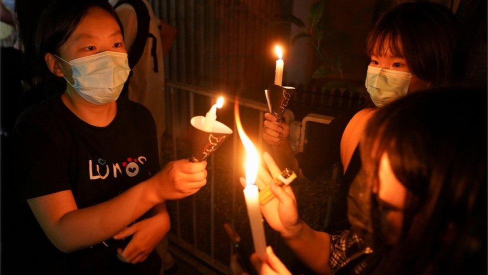 People gather with lit candles near Victoria Park, June 2021