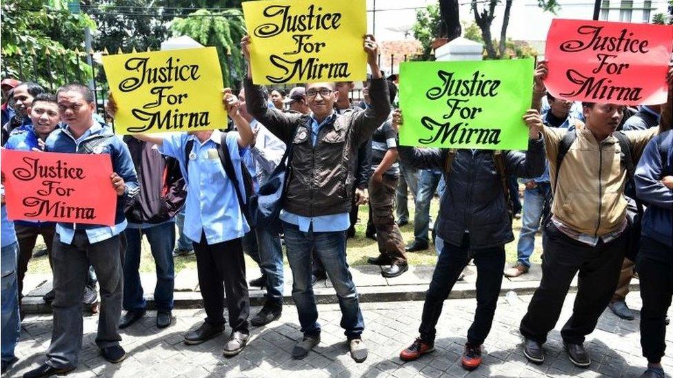 Relatives of victim Wayan Mirna Salihin hold signs outside the Central Jakarta court on 27 October 2016.