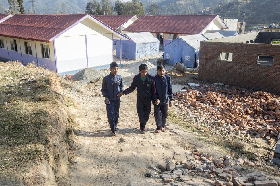 Saroj Raygiri (15) and Badal Ranamajar (14) help Sandesh up the hill to the school canteen