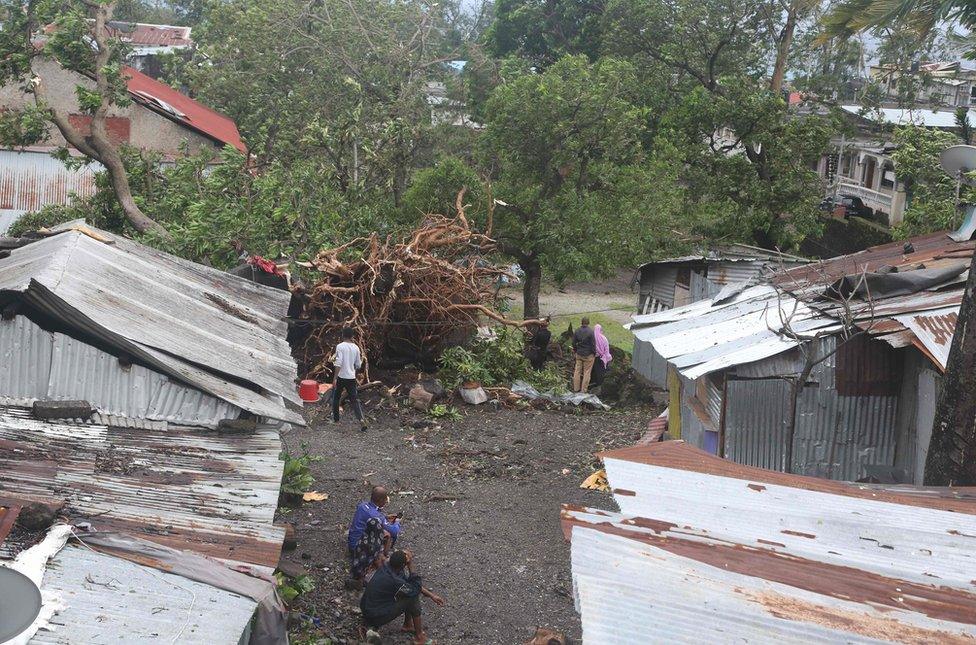 People stand by damaged houses and fallen trees after tropical storm Kenneth hit Comoros