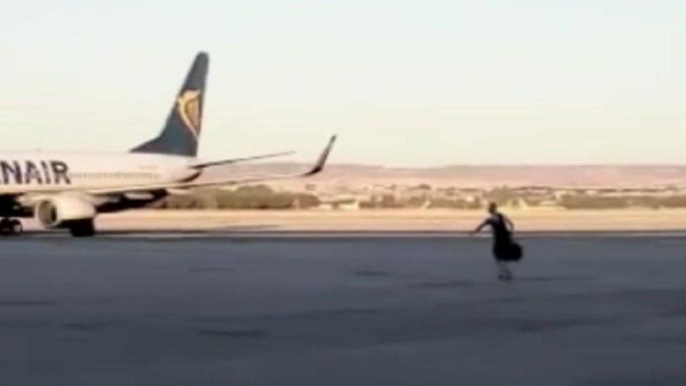 Man alone on tarmac running towards plane