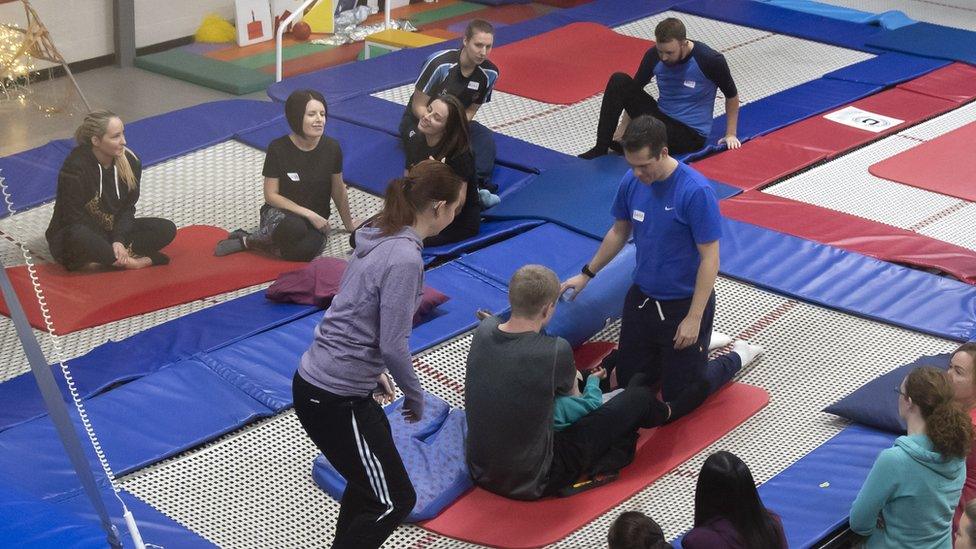 A couple of members of staff supporting a student on the trampoline