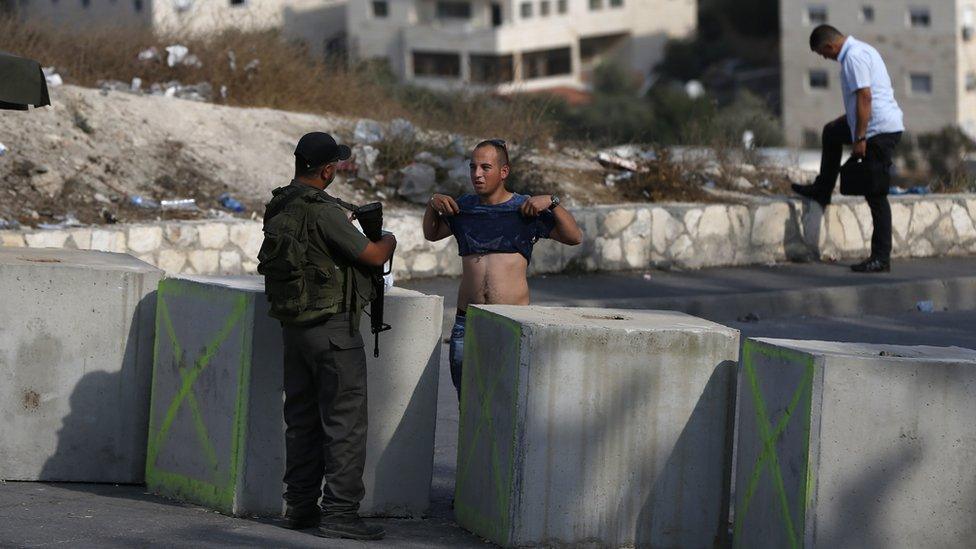 An Israeli border guard inspects a Palestinian man at a newly erected checkpoint at the exit of the east Jerusalem neighbourhood of Issawiya on October 19, 2015