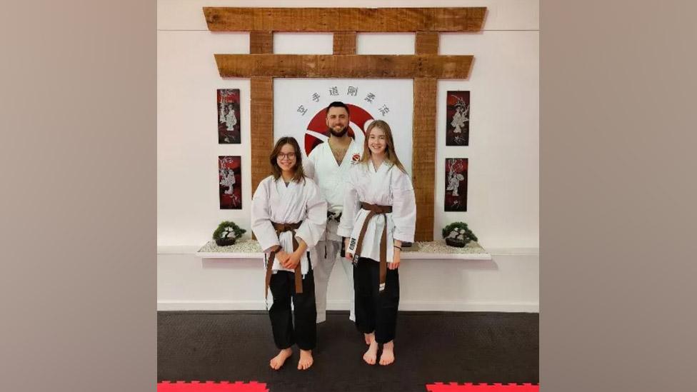 Sensei Aaron Milan-Vega and two girls wearing black trousers