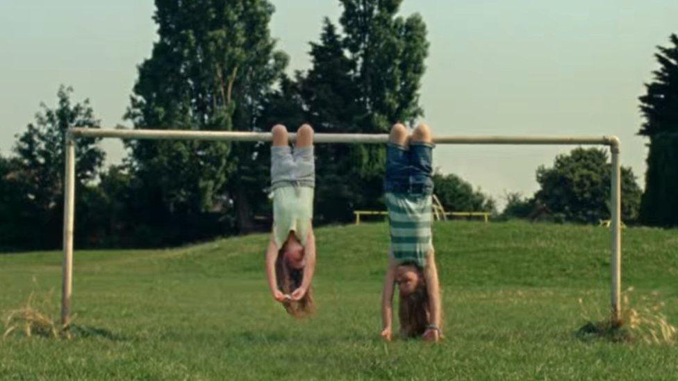 Undated screen grab from Advertising Standards Agency of Dairylea TV advert which shows two girls hanging upside down from a football goal before one opened the cheese triangle snack and ate it, has been banned following complaints that it could encourage unsafe behaviour.