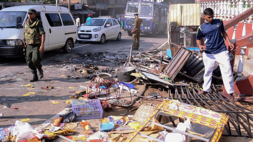 Sri Lankan police commandos patrol next to debris of from a damaged shop in the central district of Kandy on March 6, 2018,