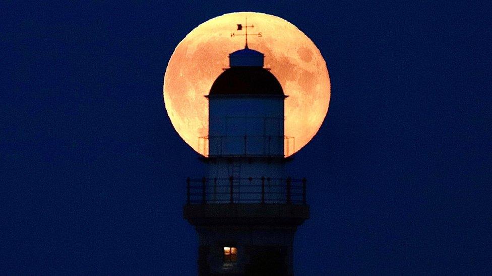 The full Moon behind a lighthouse