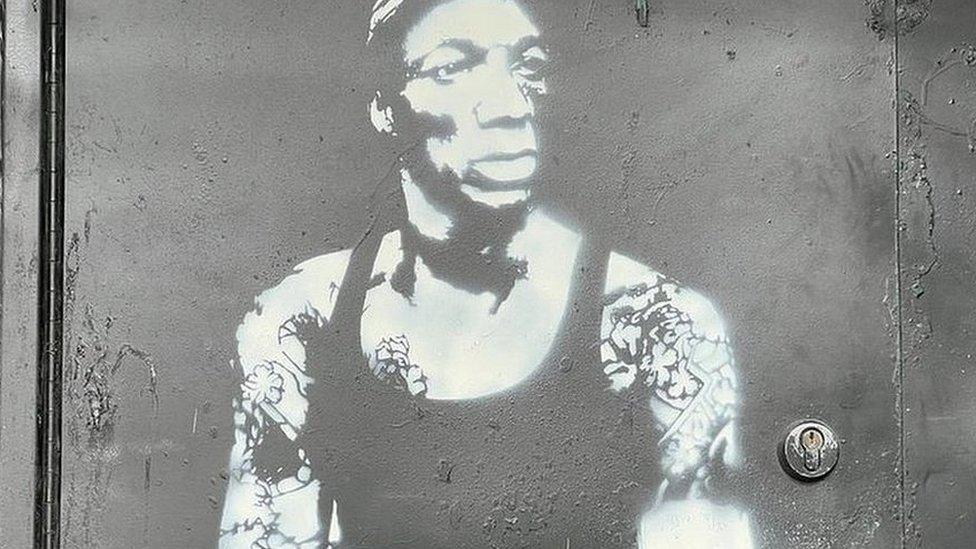 White spray painted mural of Bristol rapper Tricky on a black wall