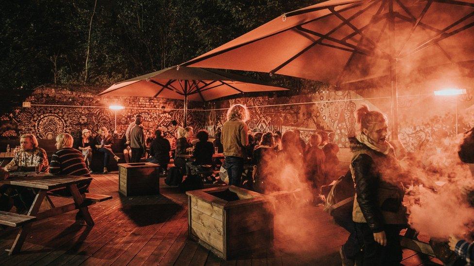 People chatting at tables and benches outside in a beer garden