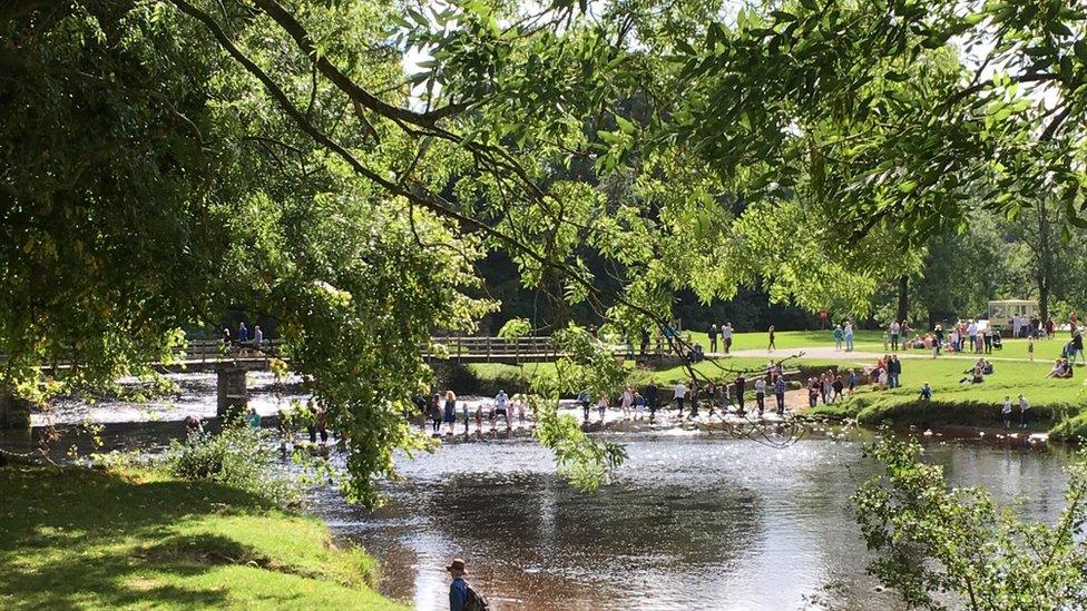 People walking across a river using stepping stones (Image: BBC)