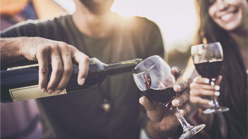 Man and women filling glasses with red wine