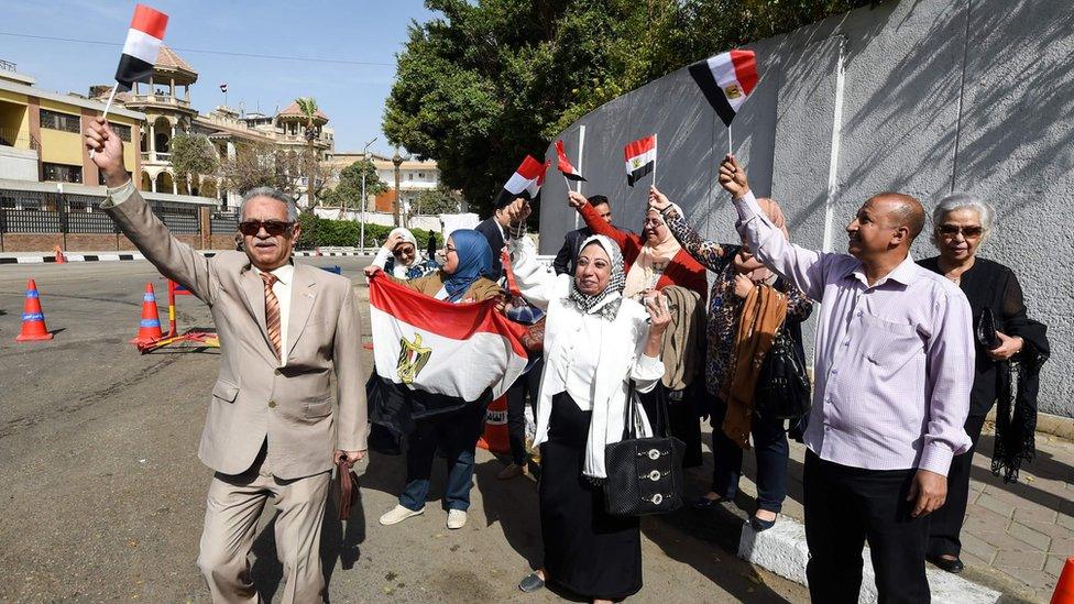 Egyptians hold up national flags in Heliopolis, Cairo (26 March 2018)