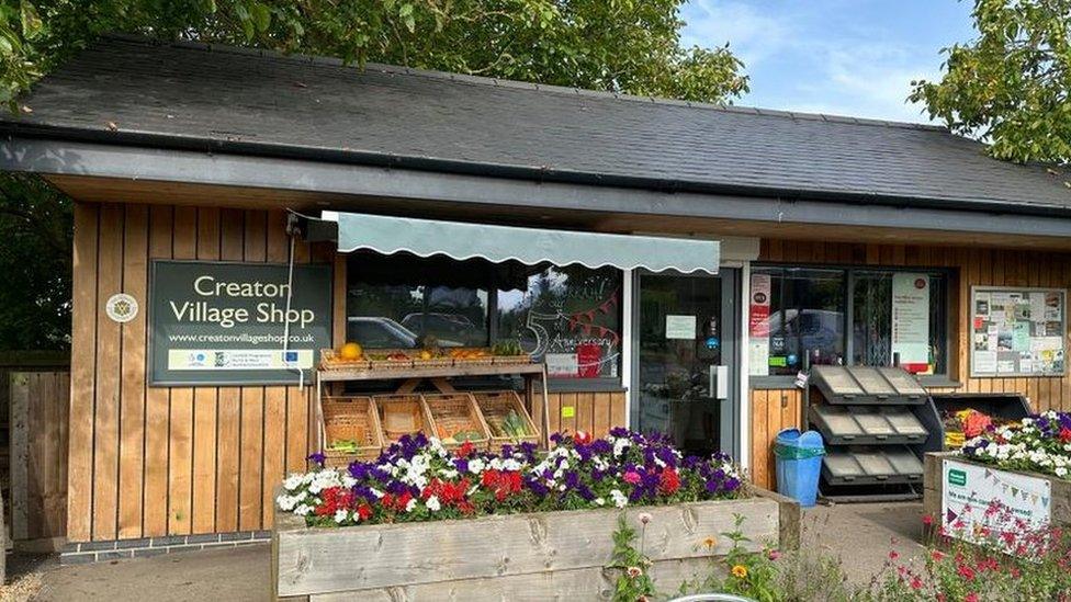 Small single-storey wooden shop building with flowers outside