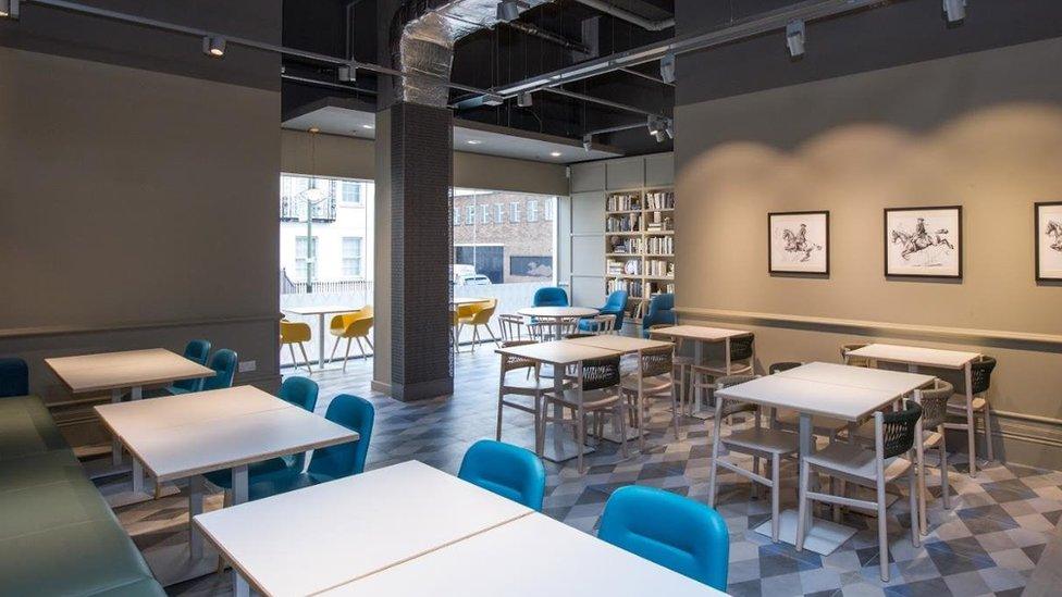 An empty cafe with blue chairs and white tables