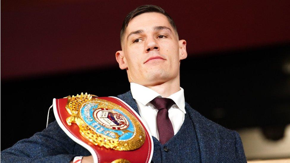 Chris Billam-Smith wearing a suit and tie and holding his WBO title belt