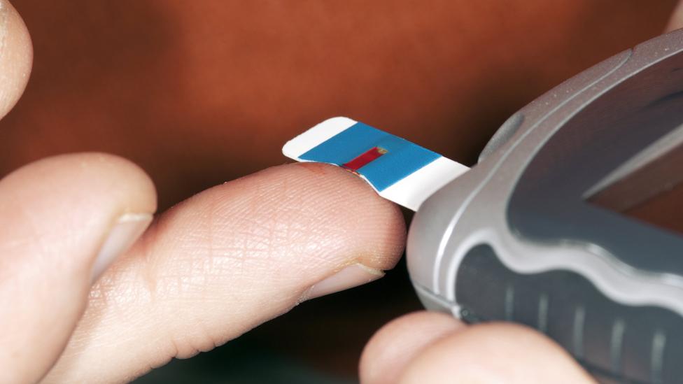 Blood from the tip of a pricked finger is placed on a diagnostic strip to test for blood sugar (glucose) levels in a diabetic patient