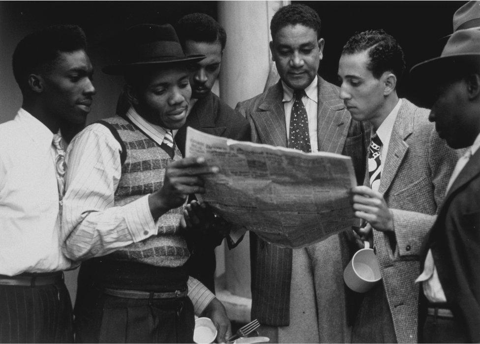 Passengers on the SS Empire Windrush reading a newspaper