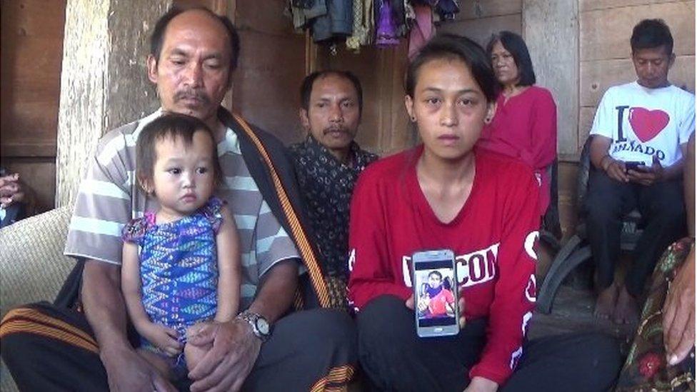 Anita Limbu Datu (R) shows a picture of her husband Alpianus, who was killed in the separatist attack