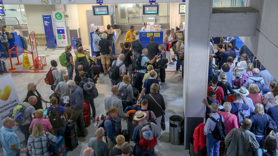 People queue in front of a Thomas Cook counter