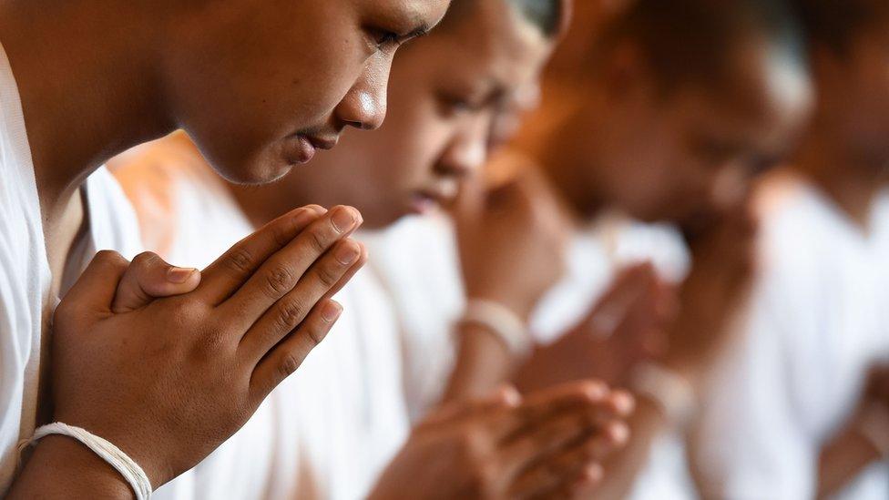 Members of the "Wild Boars" football team pray with holy string around their wrists during a ceremony to mark the end of the players" retreat as novice Buddhist monks at the Wat Phra That Doi Tung temple in the Mae Sai district of Chiang Rai province