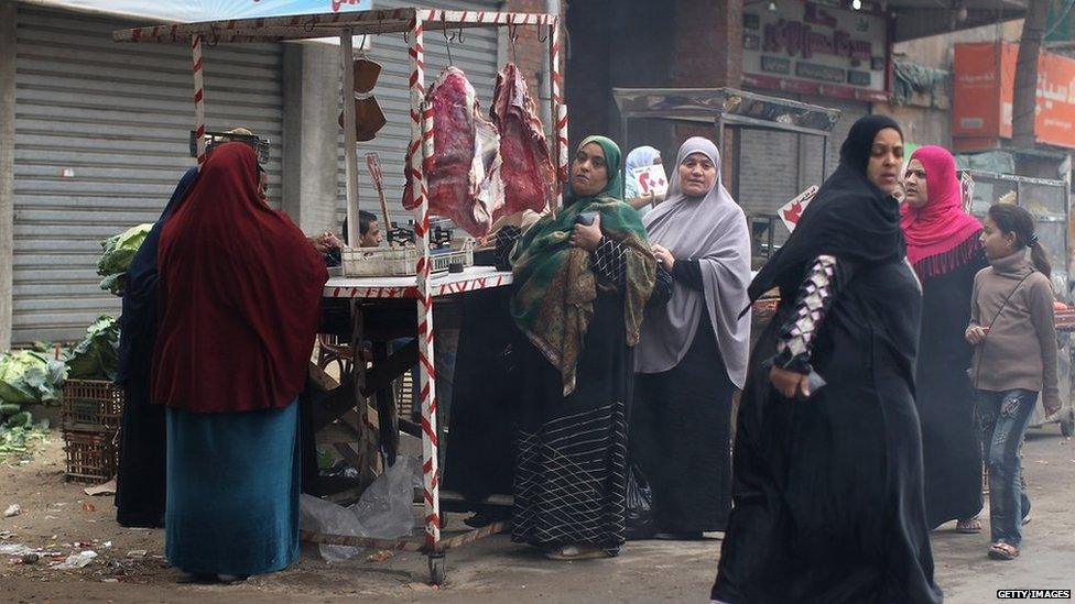 Egyptian women queue up to buy meat at a market stall