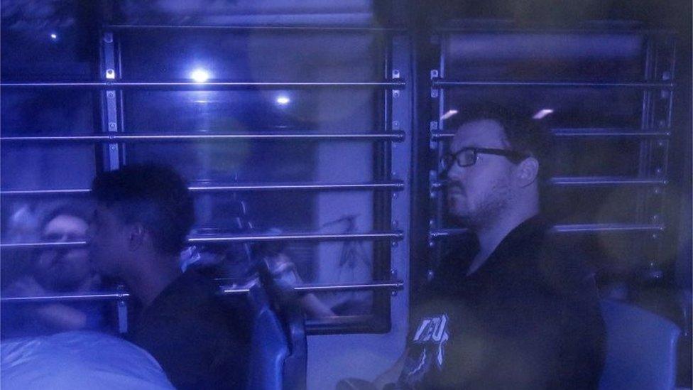 Rurik George Caton Jutting, 29, right, is escorted by police officers in an police van after his appearing in a court in Hong Kong Monday, Nov. 3, 2014. Hong Kong police said Monday that they had charged the 29-tear-old British man with killing two women, including one whose body was found inside a suitcase on the balcony of the man's upscale apartment. (AP Photo/Vincent Yu)