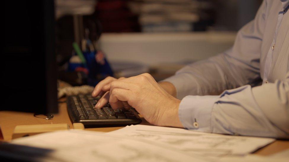 Man types at keyboard at night