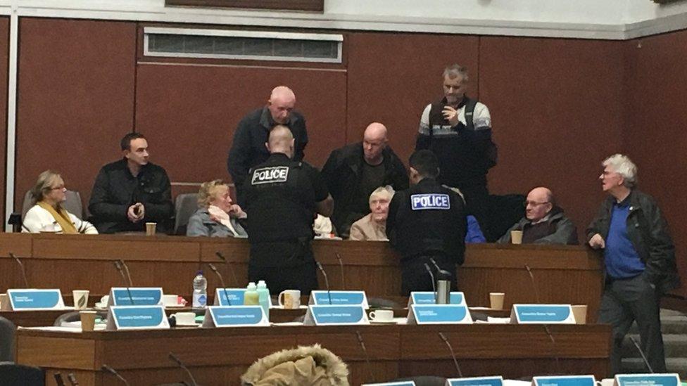 Police officers speaking to members of the public in the gallery of the council chamber