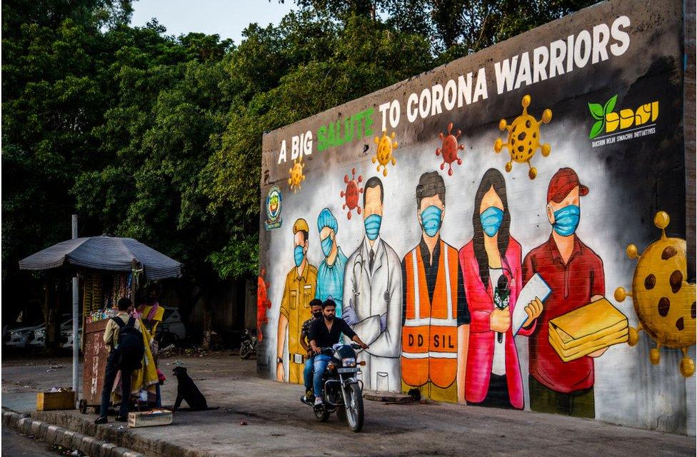 A motorcyclist passes by a mural celebrating India's "covid warriors" in Delhi on 8 June