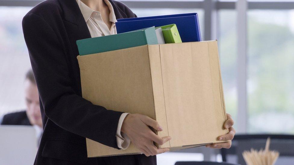 A woman carries a box after losing her job