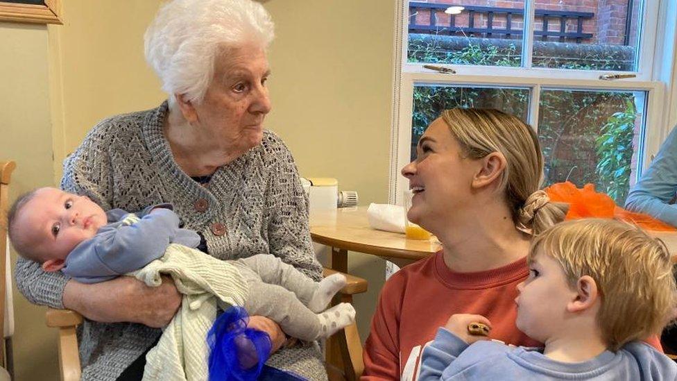 Bernice holding a child with a mother and her child