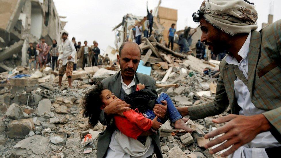 A man carries a girl rescued from the site of a suspected Saudi-led air strike that killed eight members of her family in Sanaa, Yemen (25 August 2017)