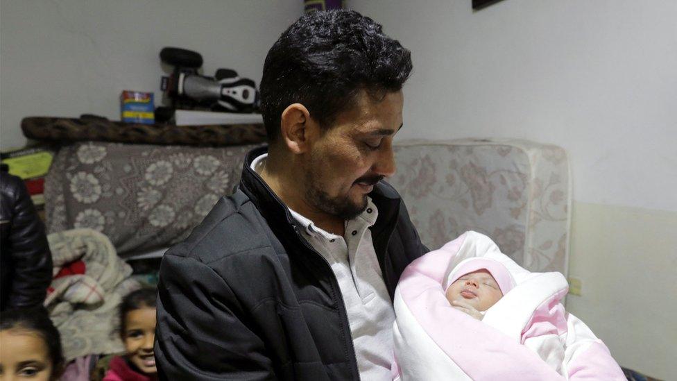 Man holding baby wrapped up in pink blanket