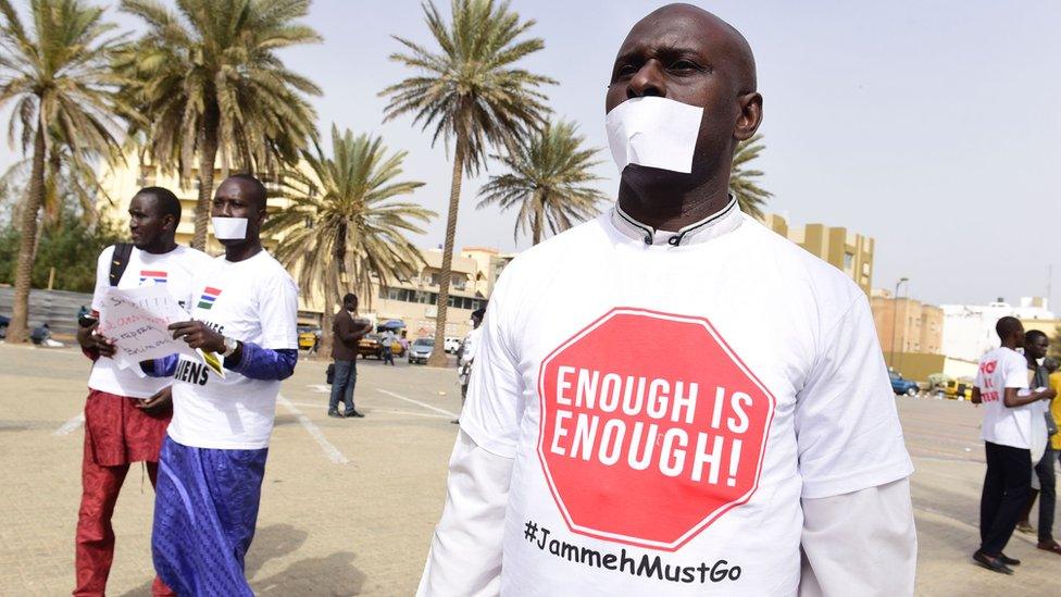 Protesters cover their mouths with pieces of papers.