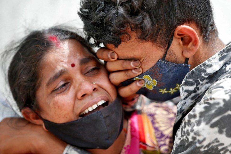 A woman mourns with her son after her husband died due to the coronavirus disease (COVID-19) outside a mortuary of a COVID-19 hospital in Ahmedabad, India, April 20, 2021.