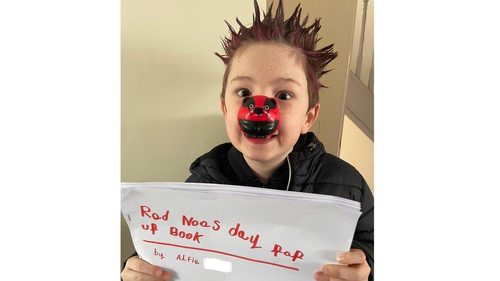 Boy with spiky hair and paper book he's made