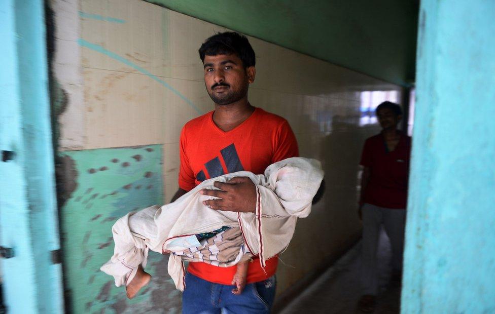 Indian man holds the body of a child