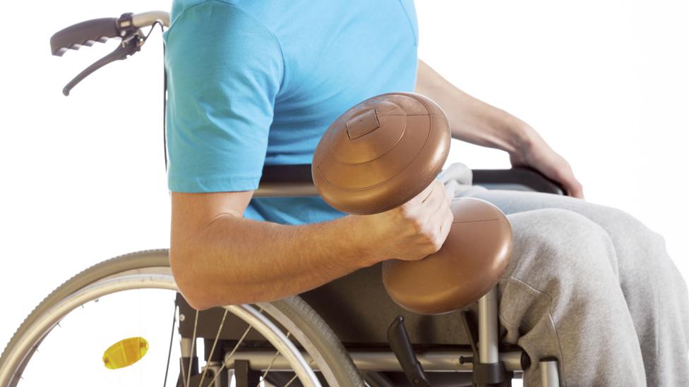 Man in wheelchair doing curls with dumb bell