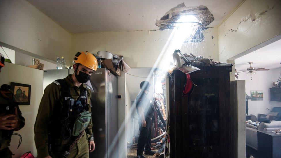 Israeli soldiers work at a building damaged by a rocket launched from the Gaza Strip, in Ashdod, southern Israel (11 May 2021)