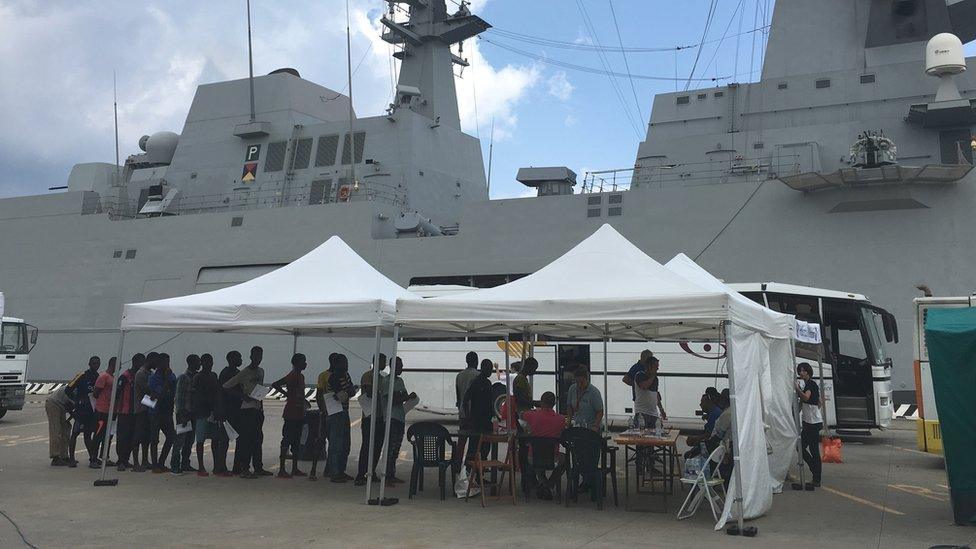 Asylum seekers from Libya queue after being brought to Messina on a rescue ship