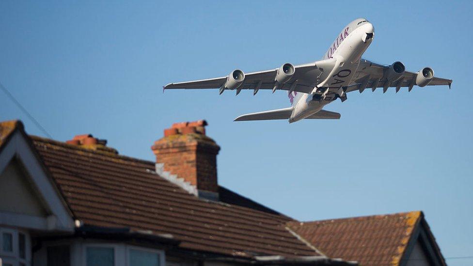 An aircraft flies over homes in Feltham after taking off from Heathrow Airport