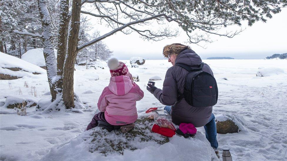 A child and father drink tea and enjoy nature in the snow