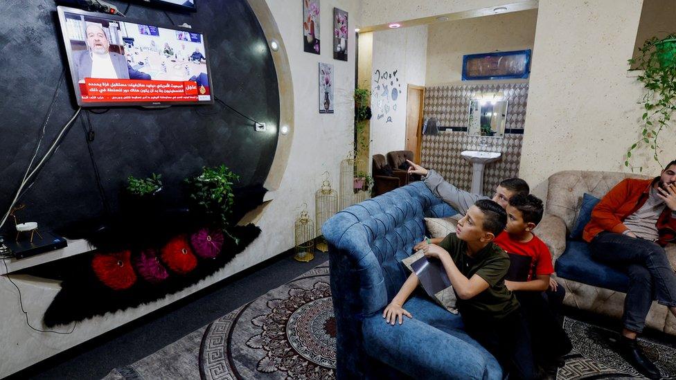 The family of a young Palestinian prisoner watch a TV for news about Israel's release of Palestinian prisoners in exchange for hostages held by Hamas, near Hebron in the occupied West Bank (21 November 2023)