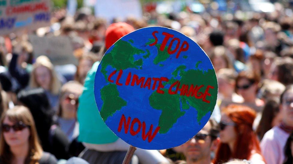 Students hold up a sign with the slogan "stop climate change now" during a protest in Vienna, Austria