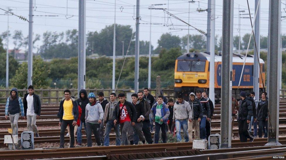 Migrants make their way along train tracks as they attempt to access the Channel Tunnel in Frethun, near Calais, France,