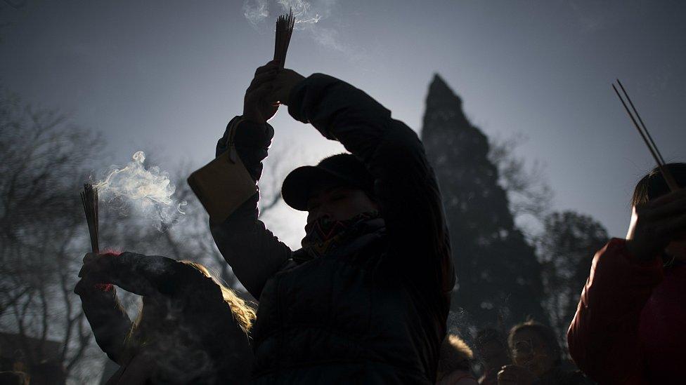 People pray with incense sticks to celebrate the Lunar New Year, marking the Year of the Dog, at the Lama temple in Beijing on February 16, 2018